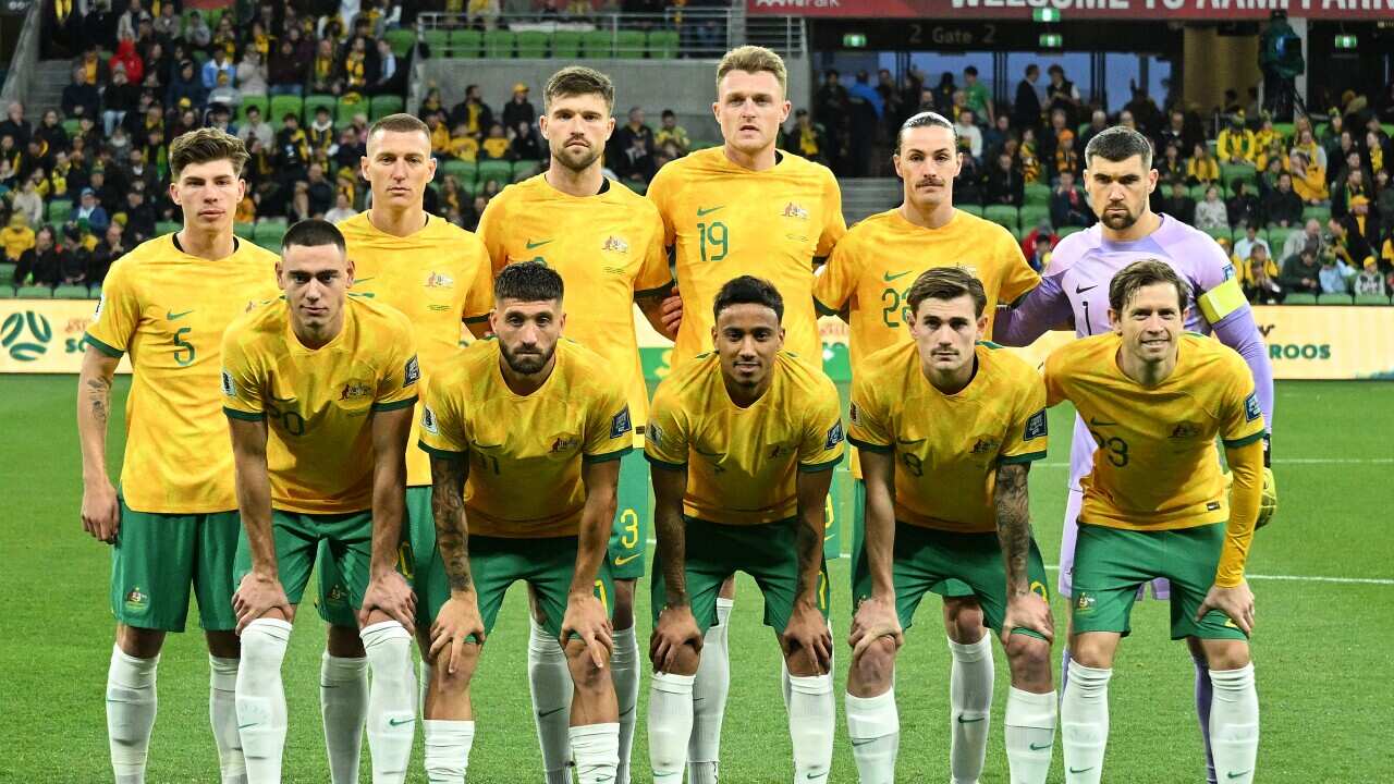 The Socceroos team pose on the field.