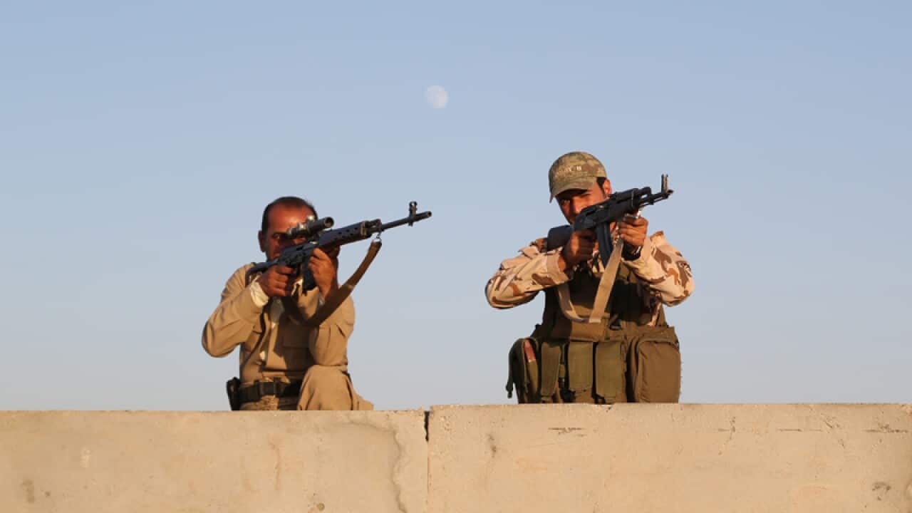Kurdish peshmerga fighters stand guard.