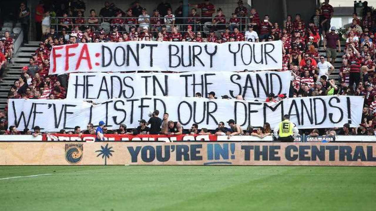 Wanderers supporters from the Red and Black Bloc are seen holding a banner.