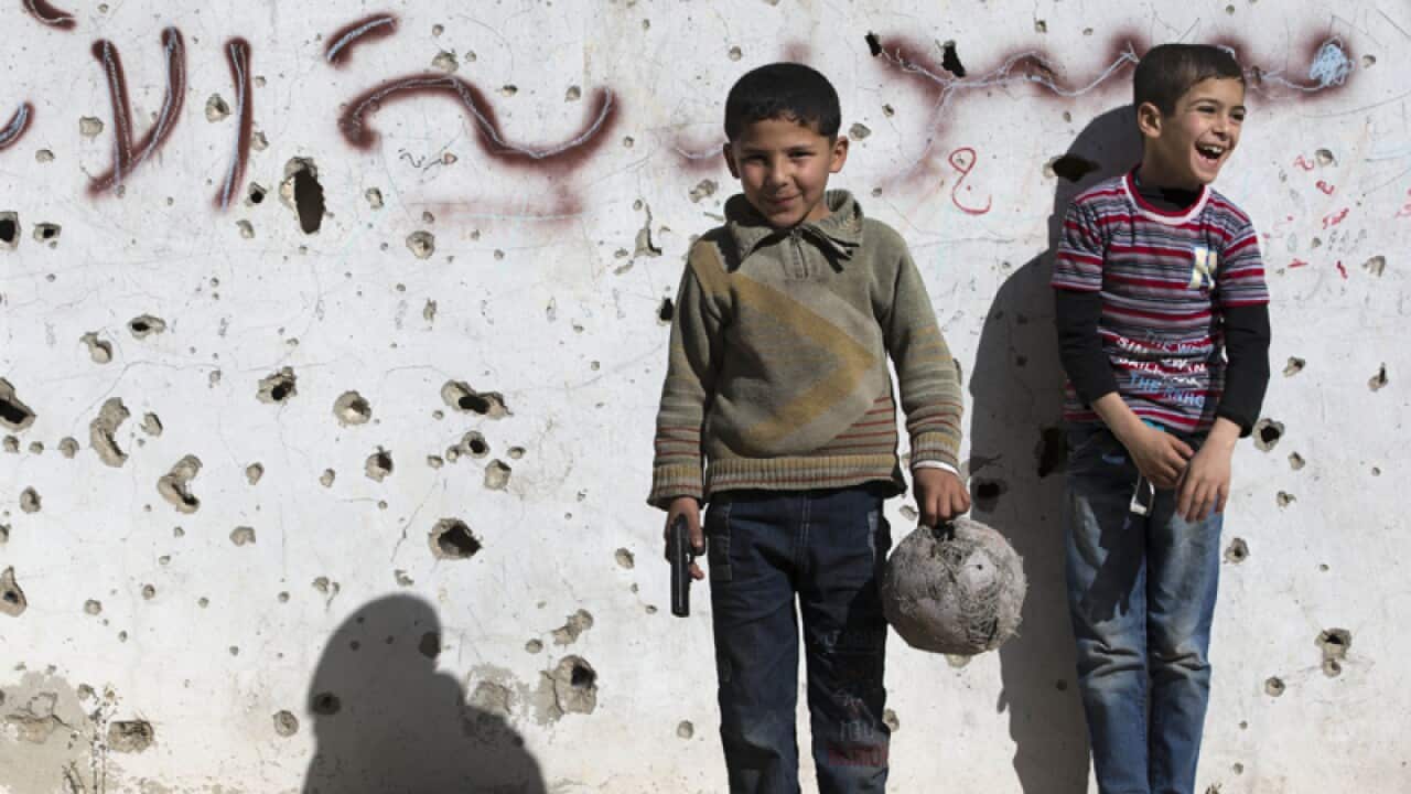 A Syrian boy holds a toy gun in the old city of Homs