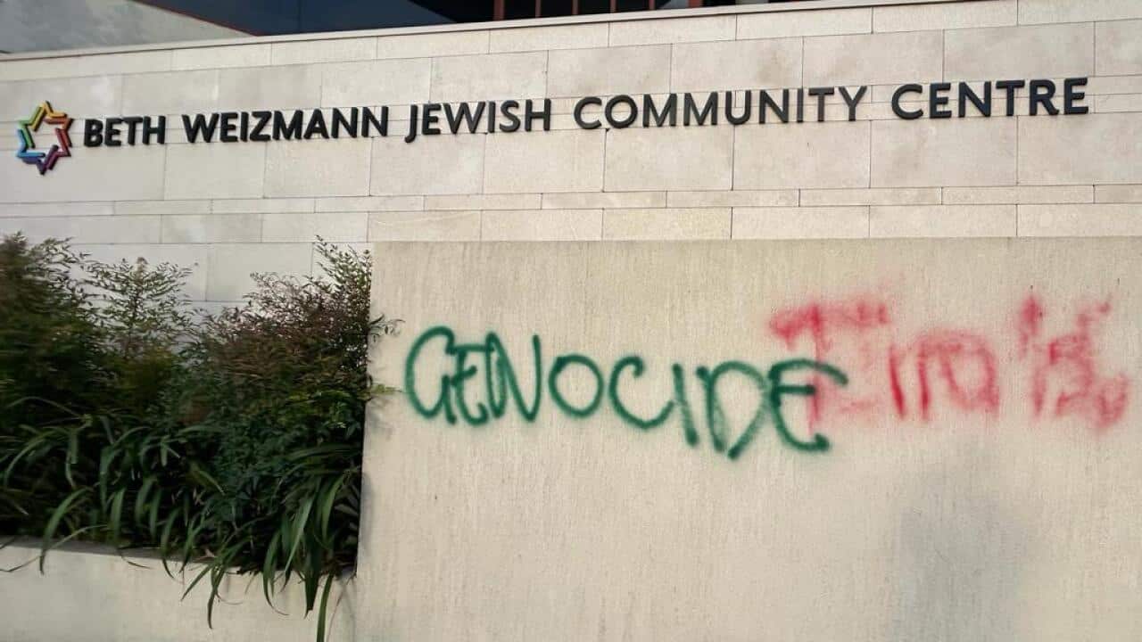 The word 'genocide' spray painted in green on a Jewish community centre wall.