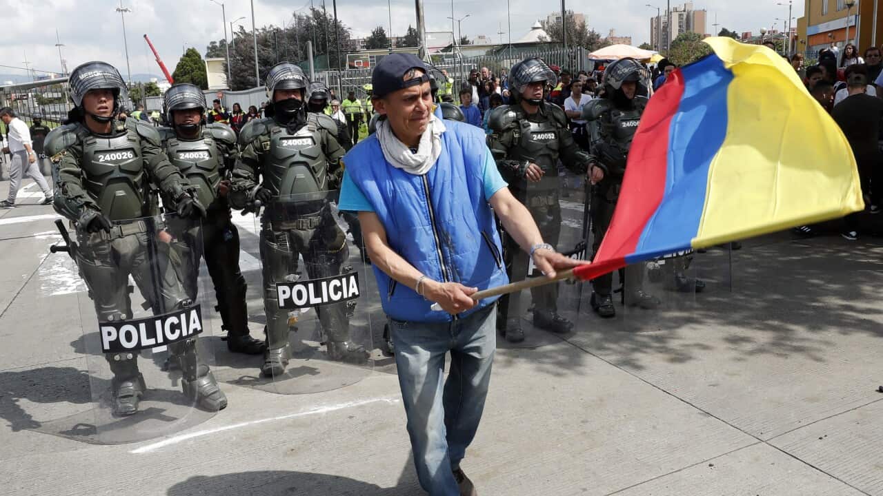 A demonstrator waves the national flag in front of anti-riot police during a national Strike protest through the main streets of Bogota, Colombia.