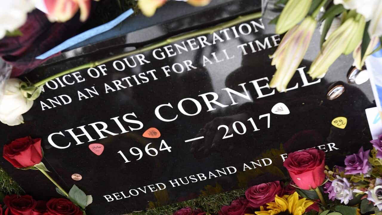 A plaque marking Chris Cornell's gravesite is covered in guitar picks and flowers.