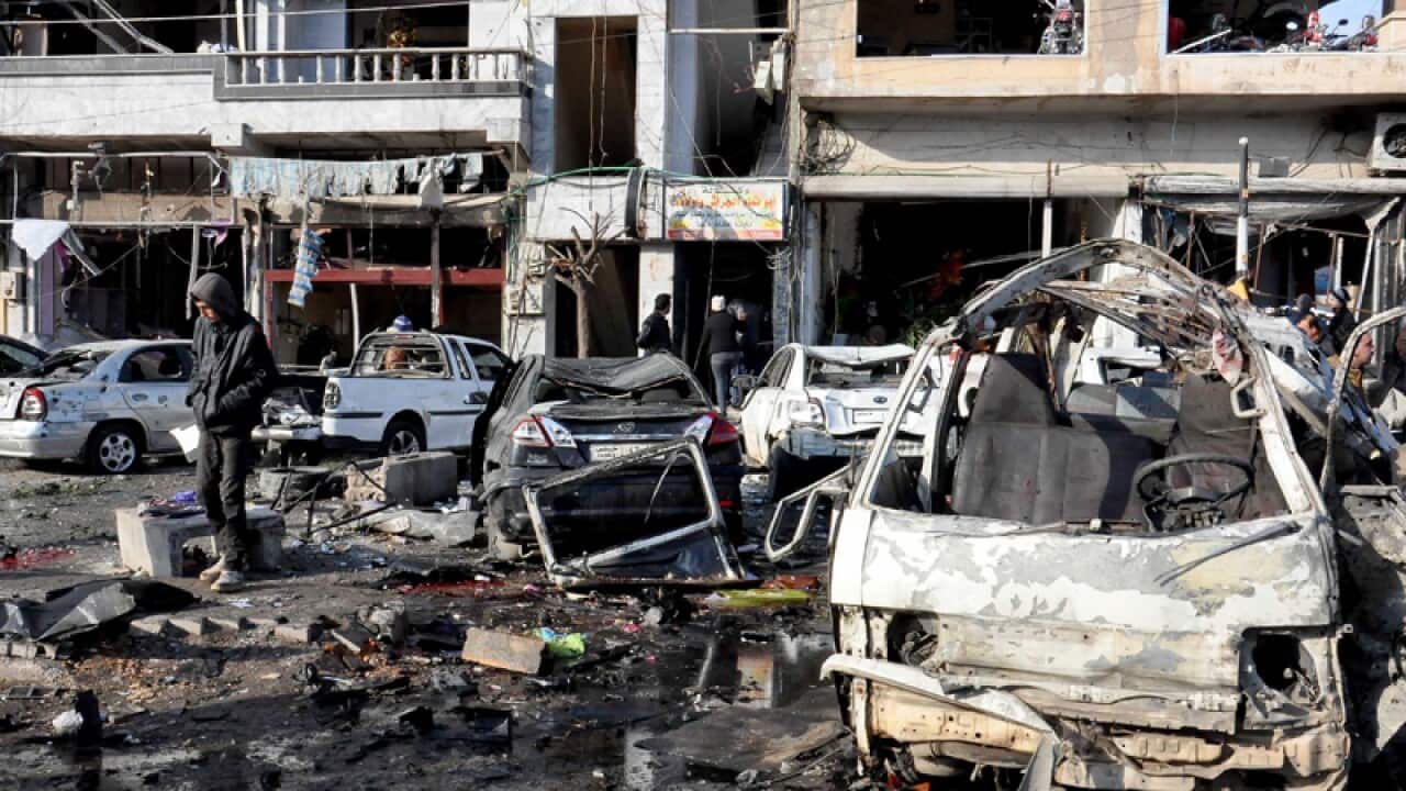 Syrian police and citizens inspect the site of two bomb attacks, Homs