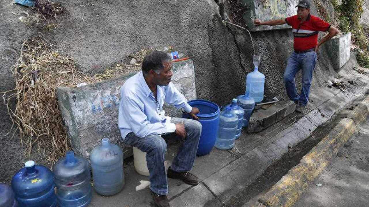 Men fill containers with water at Avila National Park during rolling blackouts