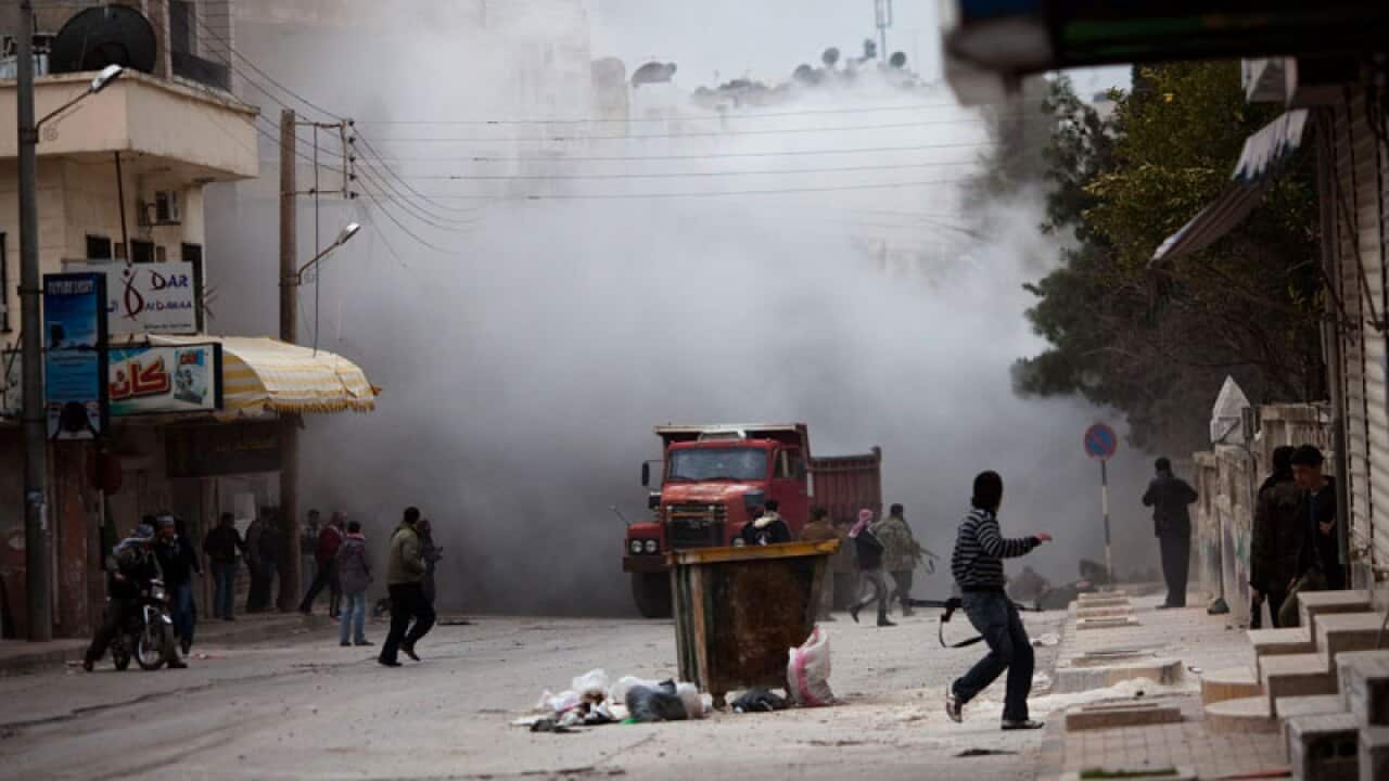 Syrian rebels are seen amid smoke after being hit by a tank during a day of heavy fighting with Syrian Army forces in Idlib, north Syria. (AAP)