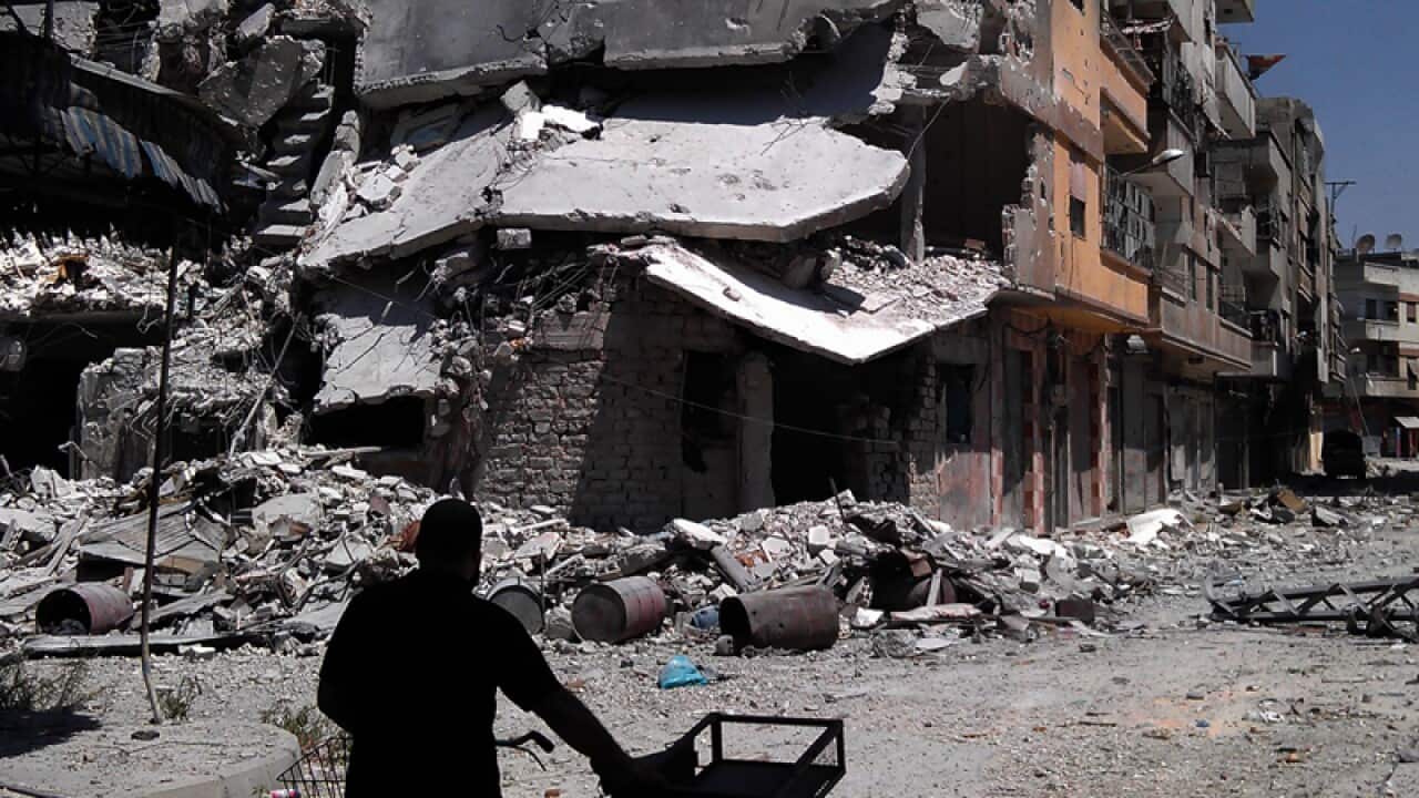 A man looks at destroyed buildings in the province of Homs