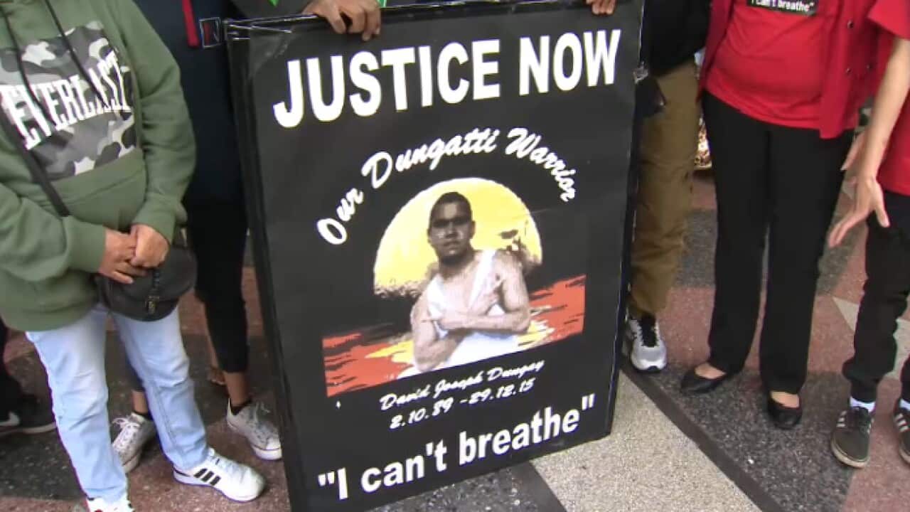Family and friends of David Dungay hold a sign outside court.