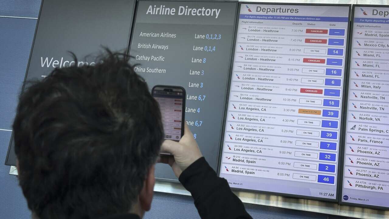 A man taking a photo of a departures board at JFK airport in New York