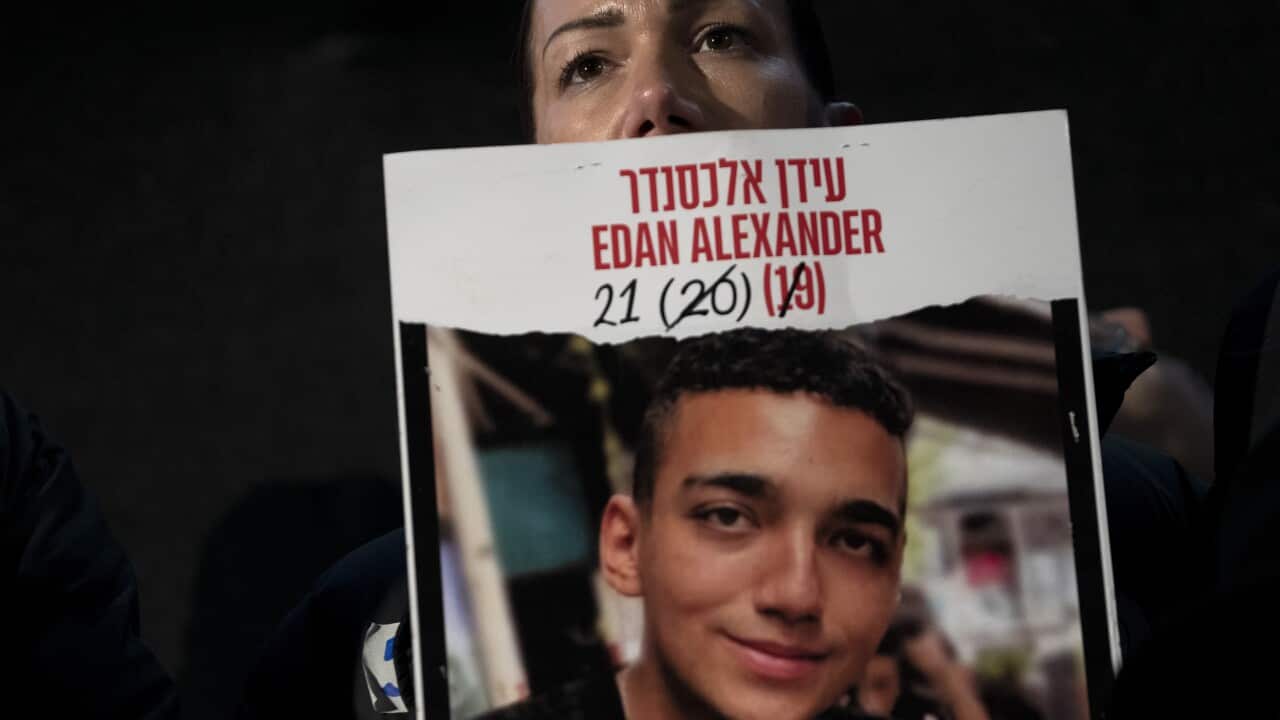 A woman holds a poster of a young boy.