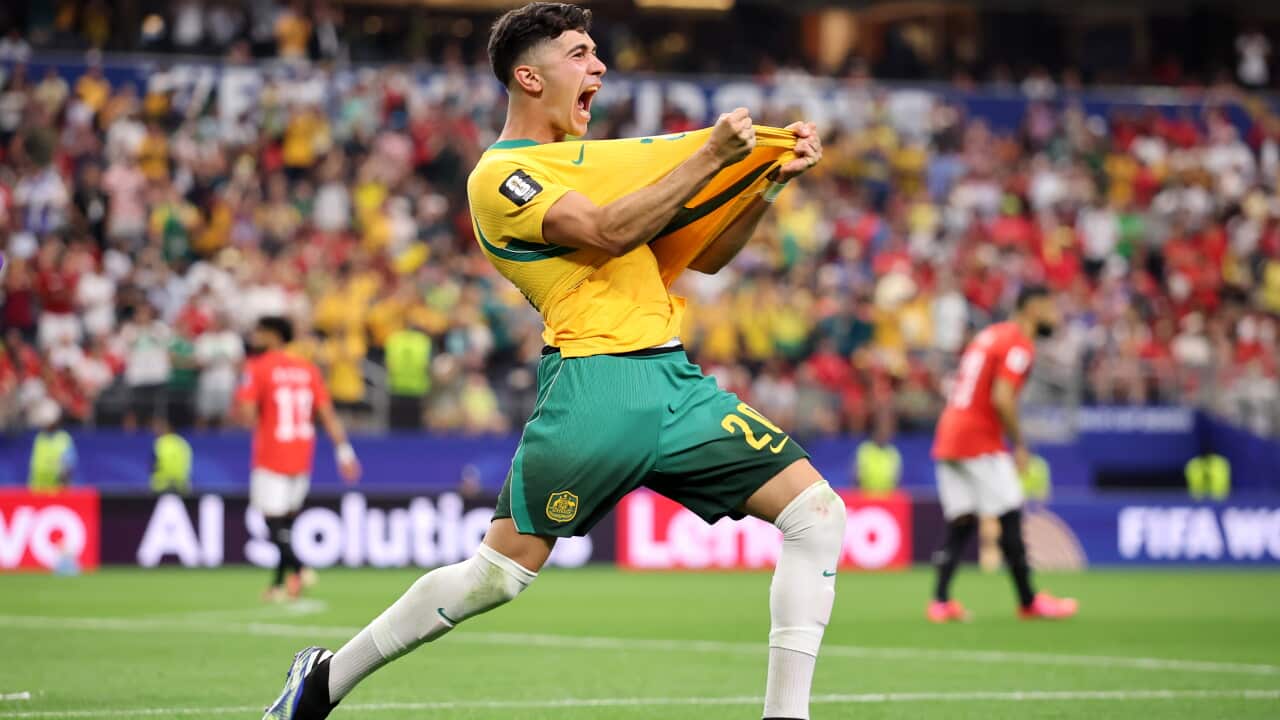A man in a yellow shirt and green shorts celebrates pulling his shirt