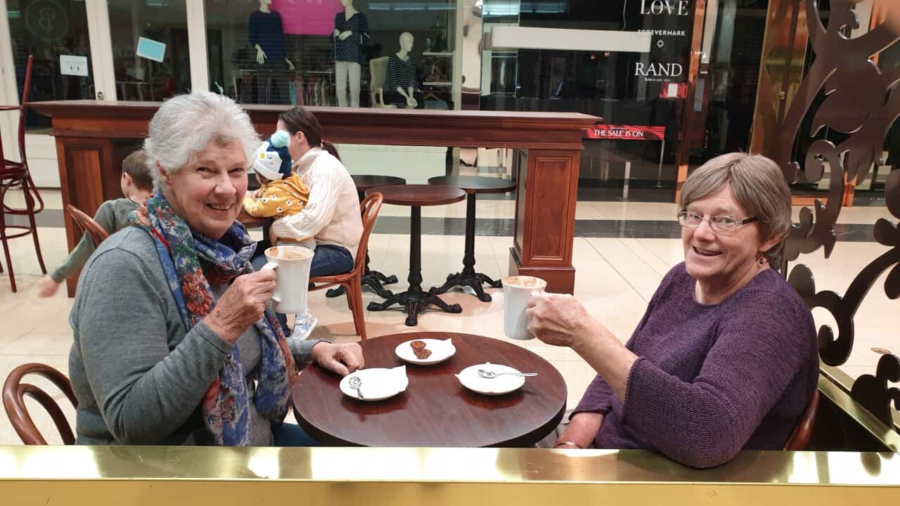 Two older women sitting down and having coffee