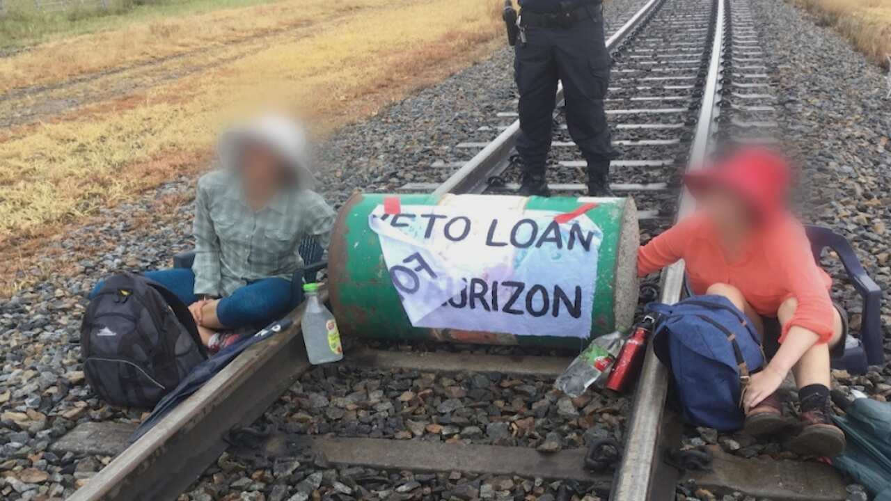 Environmental protesters blocking a rail line with a dragon's den lock-on device