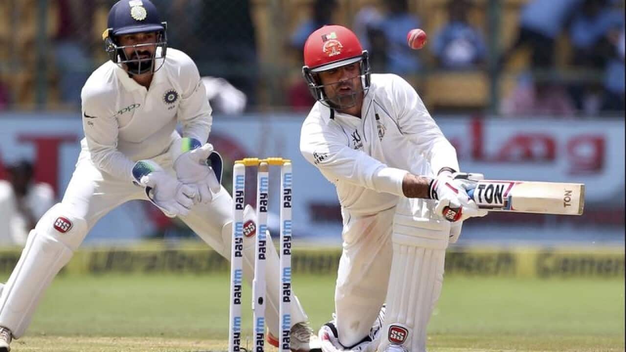 Afghanistan's Mohammad Nabi, right, plays a shot.