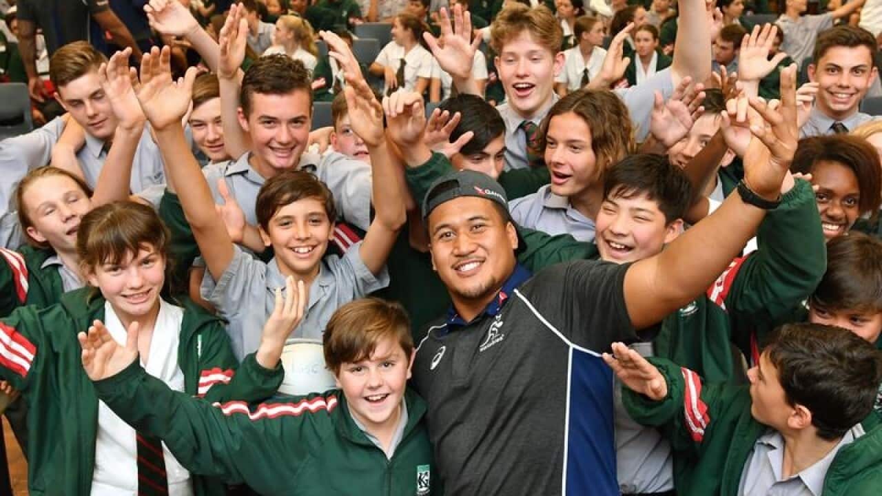 Wallabies player Brandon Paenga-Amosa posing with school students.