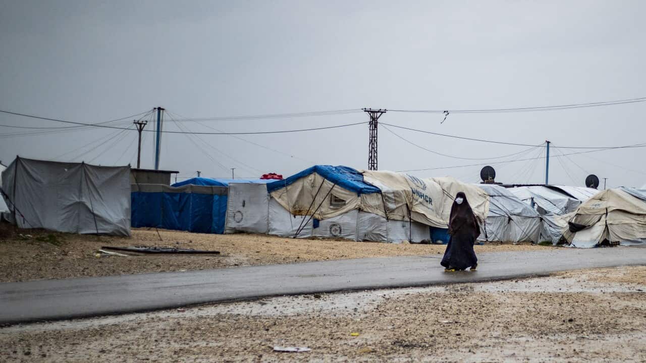 Woman walking through Al Roj camp.