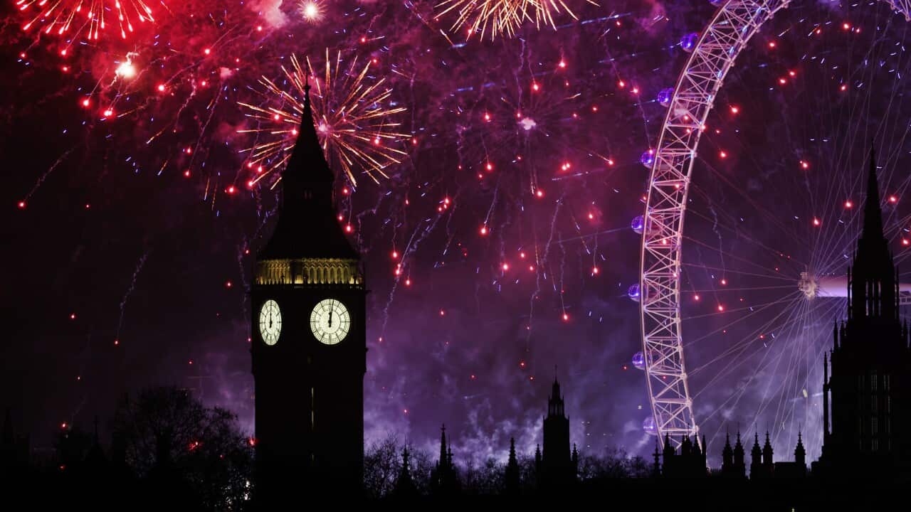 Fireworks illuminate the skyline, with a bridge and nearby buildings, as boats sail in the foreground.
