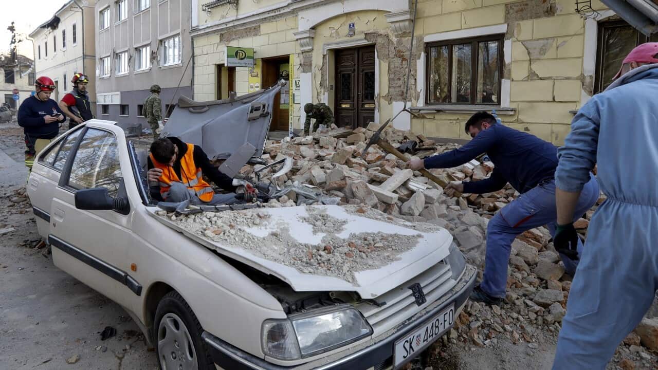 People and soldiers clear rubble following the earthquake in Petrinja