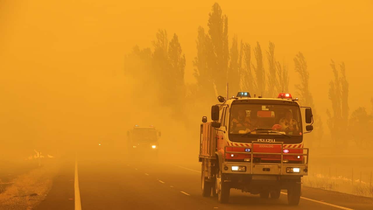 A fire truck driving along a road during a bushfire.