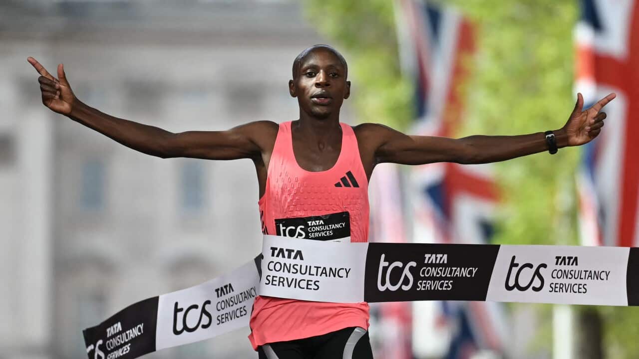 A marathon runner crosses the finish line with his hands raised