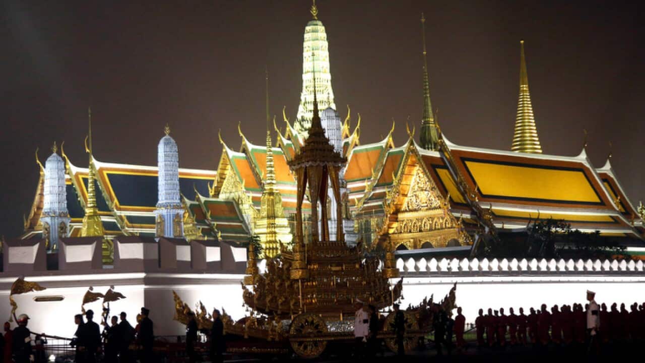 Royal officials pull the royal chariot past Bangkok's Grand Palace