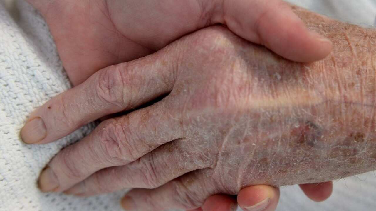 A nurse holds the hand of an elderly patient