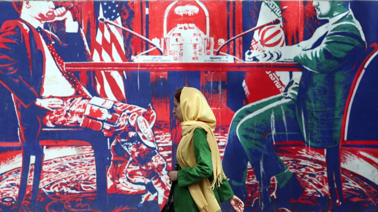 A woman walks past a large painted mural.