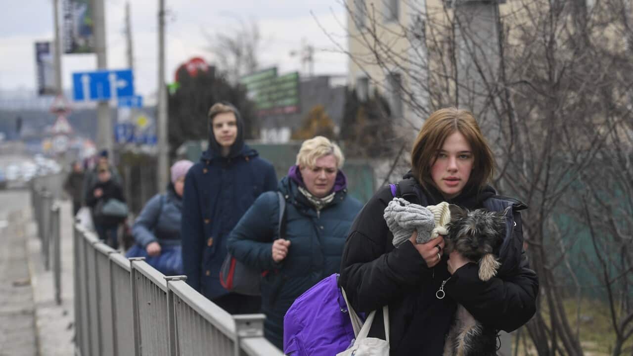 People trying to leave the city of Irpin amid collapsed structures and debris