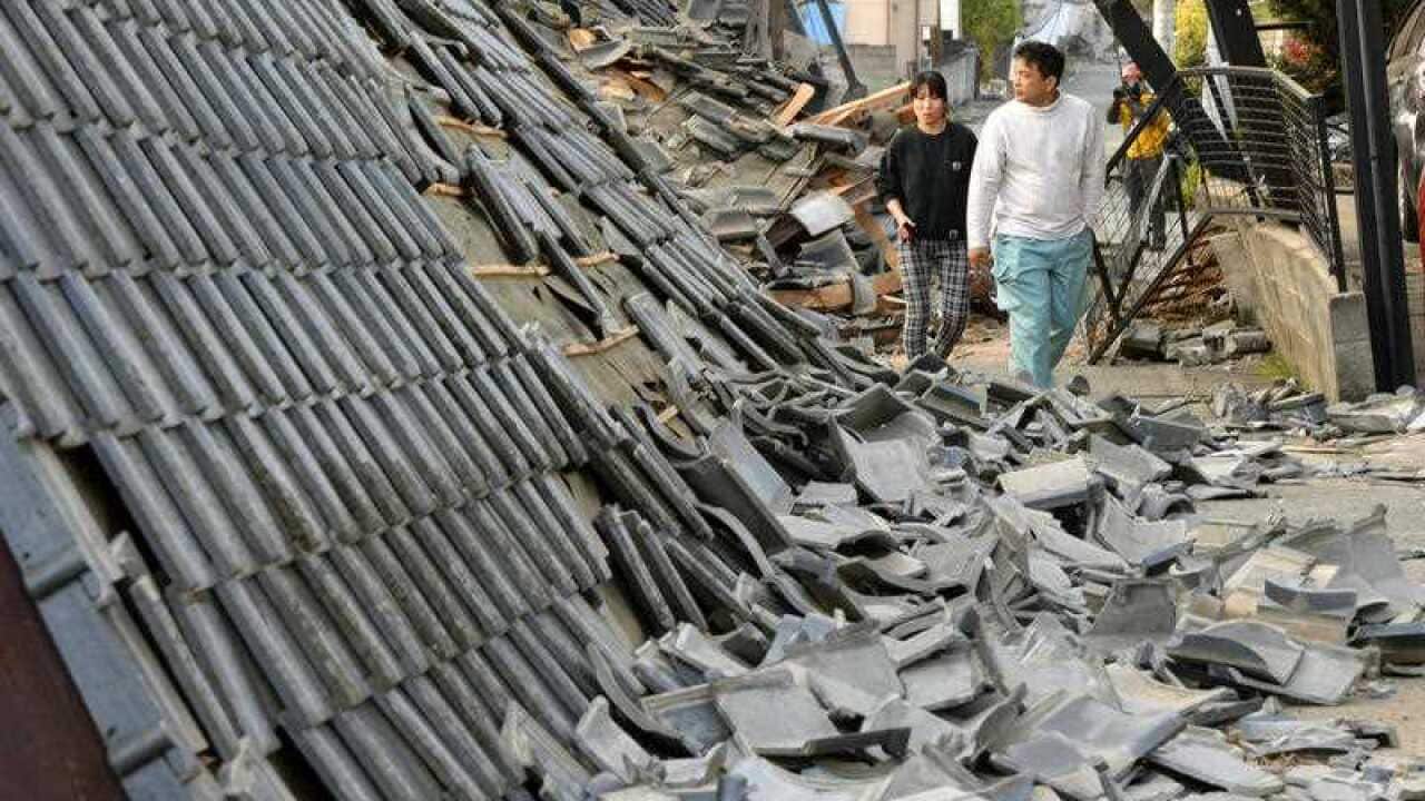 Residents walk along collapsed houses in Mashiki, Kumamoto prefecture, southern Japan, Friday, April 15, 2016, after a magnitude-6.5 earthquake.