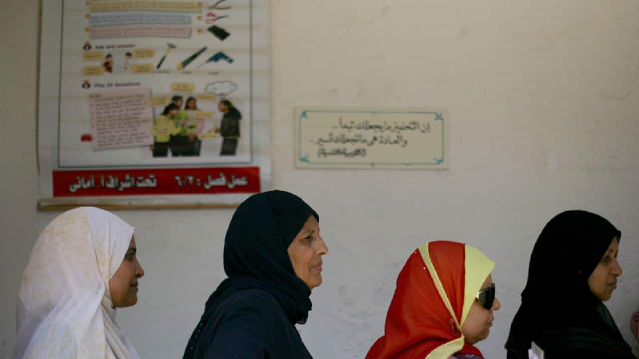 Women wait to vote at a polling station