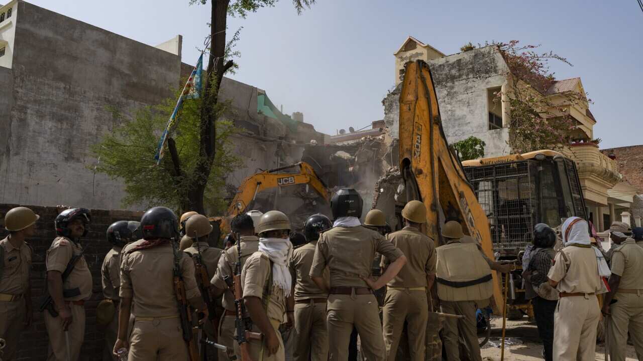 Policemen guard as authorities demolish the residence of activist Mohammad Javed which according to them have been constructed illegally in Prayagraj, India, Sunday, June 12, 2022. Javed has also been accused of involvement in violence during Fridays prot