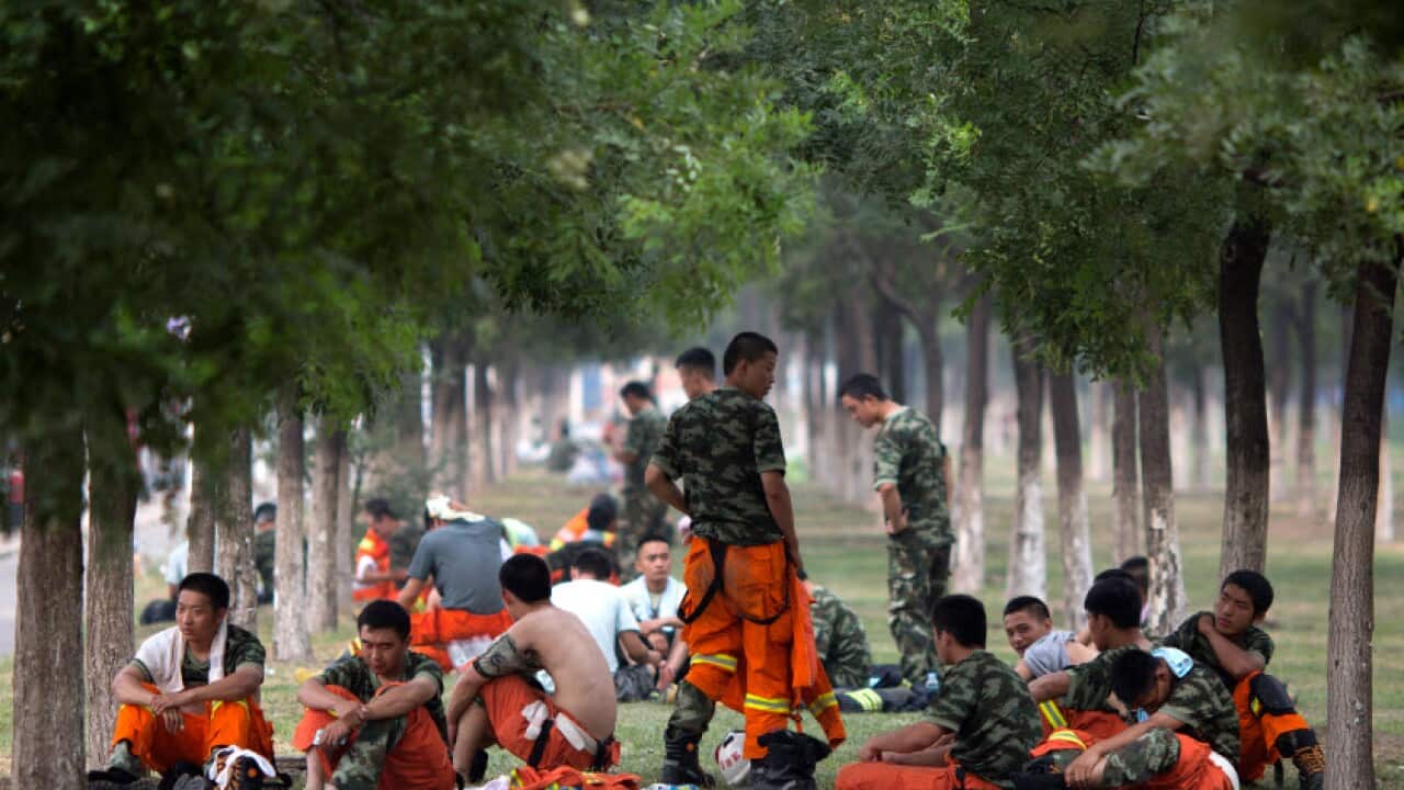 Chinese firefighters rest as they wait to be deployed near the site of an explosion in northeastern China's Tianjin municipality Saturday, Aug. 15, 2015.