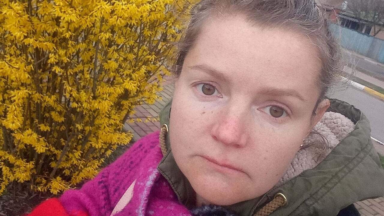 A woman standing outside taking a selfie.