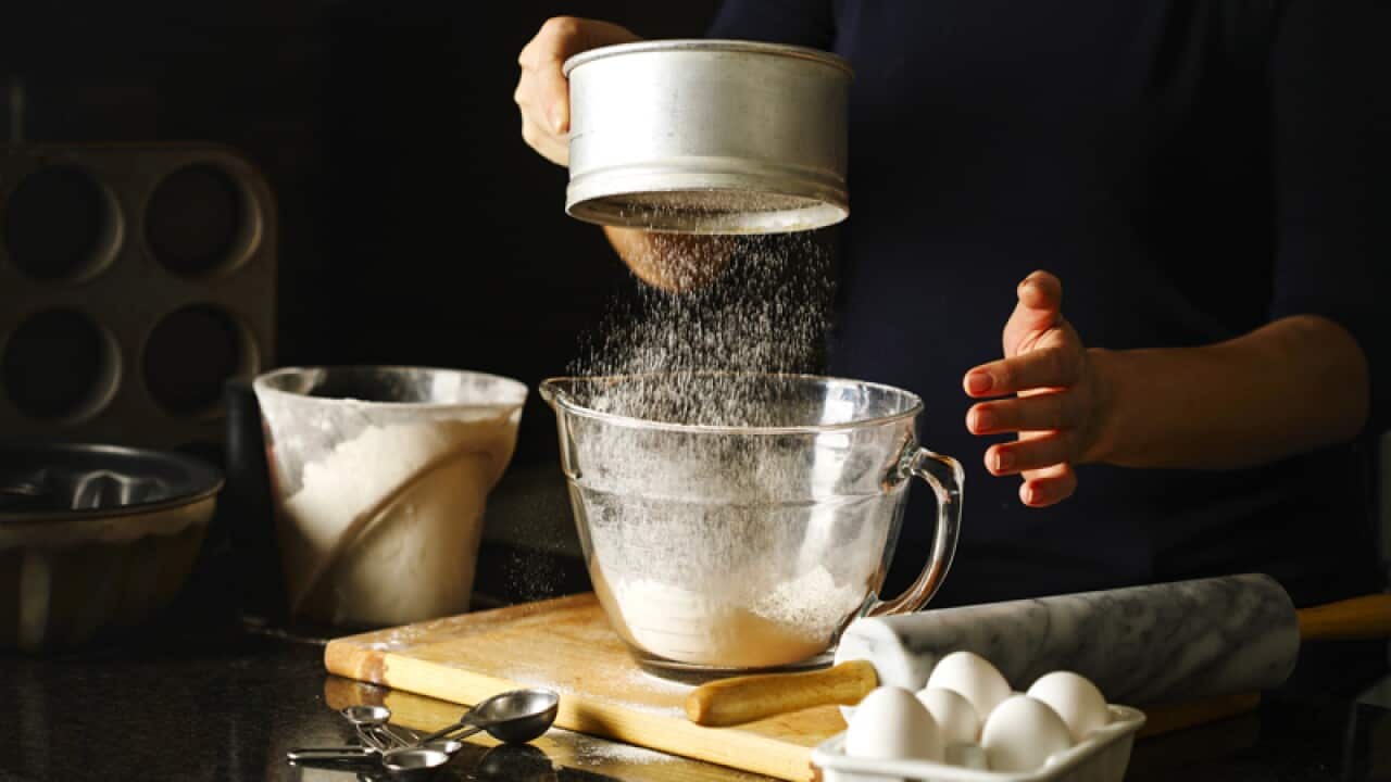 Woman sifting flour through sieve.
