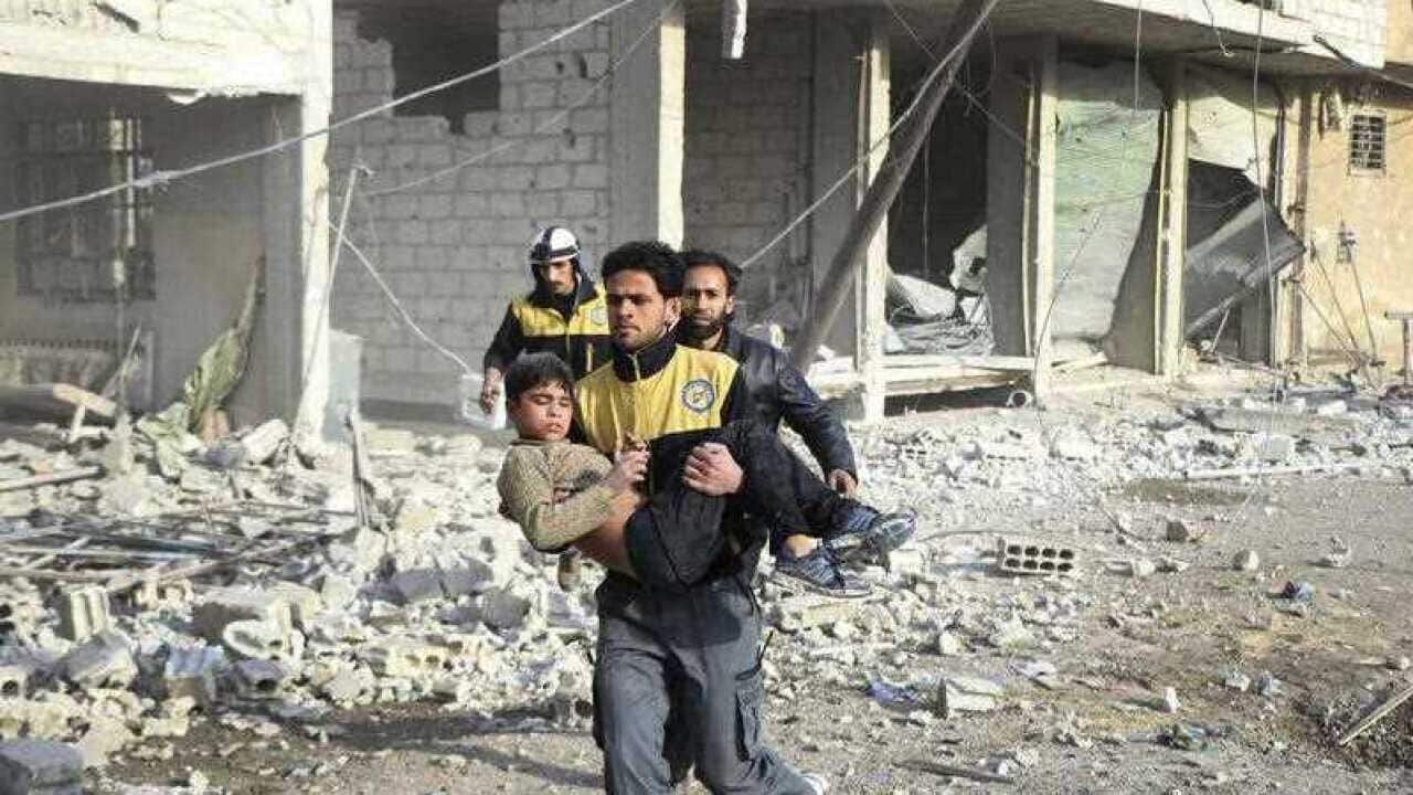 Syrian Civil Defense group carrying a boy who was wounded during airstrikes and shelling by Syrian government forces, in Ghouta