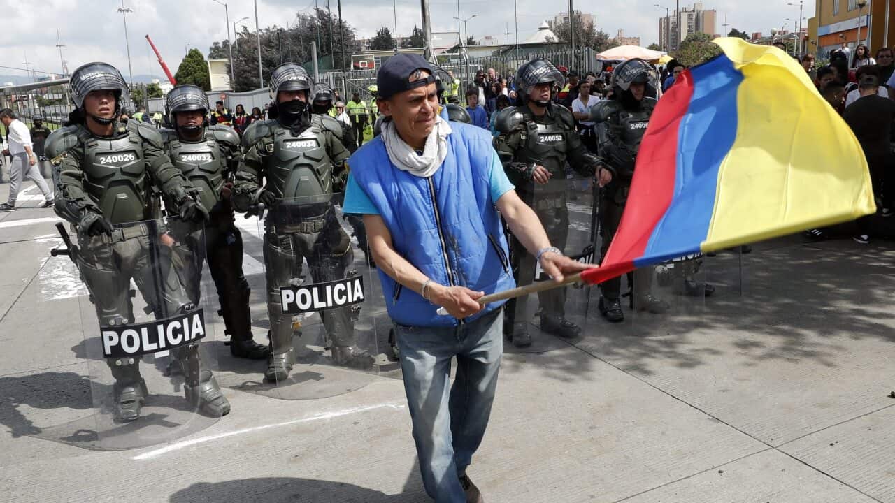 A demonstrator waves the national flag in front of anti-riot police during a national Strike protest through the main streets of Bogota, Colombia.