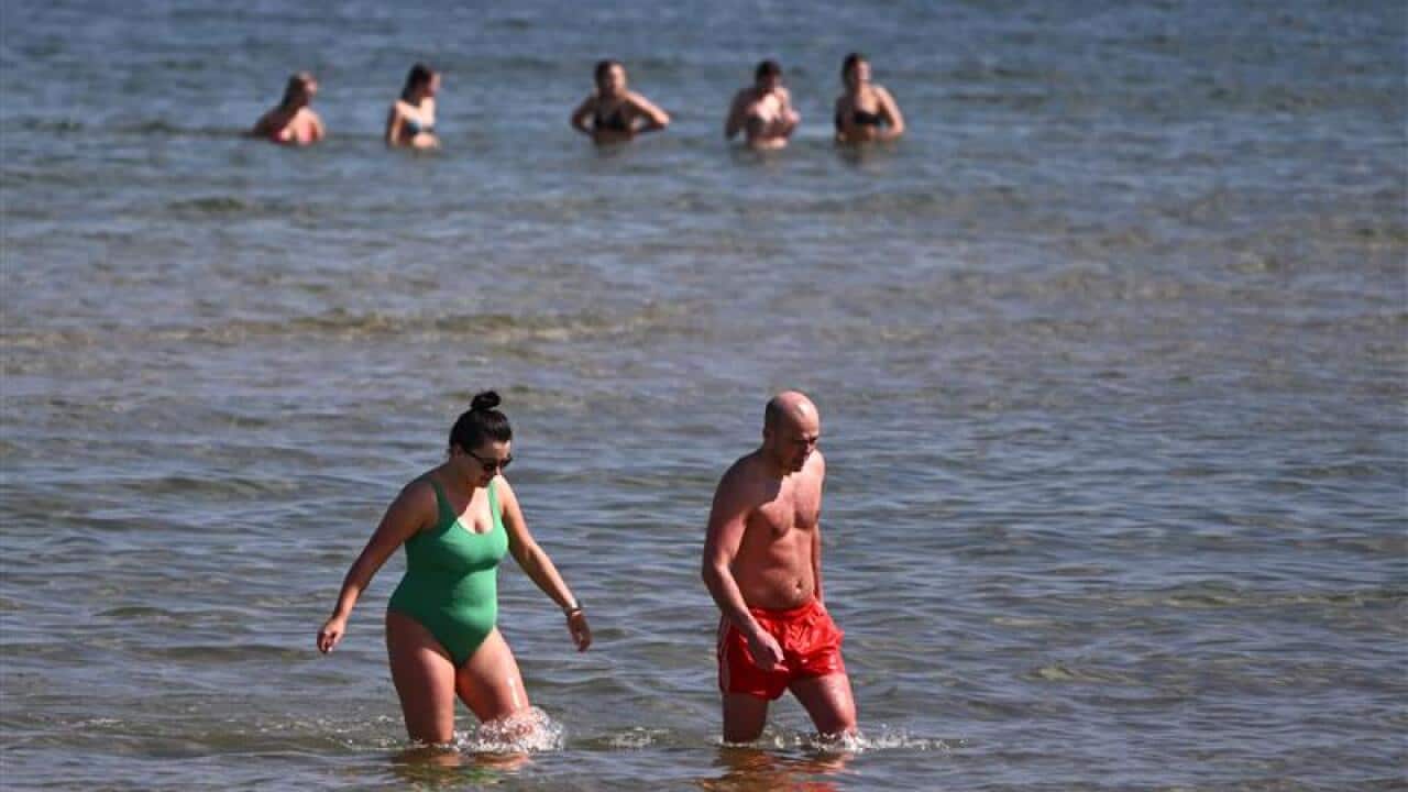 Beachgoers in the water at St. Kilda Beach in Melbourne