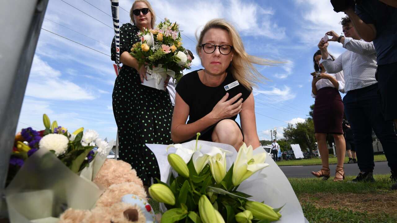 Brisbane City Cr Fiona Cunningham places flowers next to a scene a car fire which claimed the lives of multiple people, including children in Brisbane, Wednesday, February 19, 2020. (AAP Image/Dan Peled) NO ARCHIVING