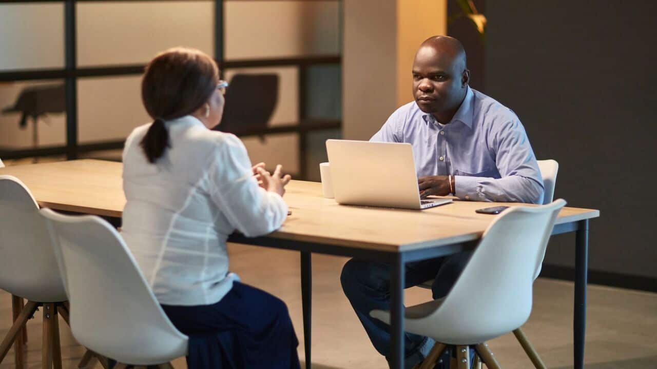 Male and female South African businesspeople discussing ideas at conference table in open plan office.