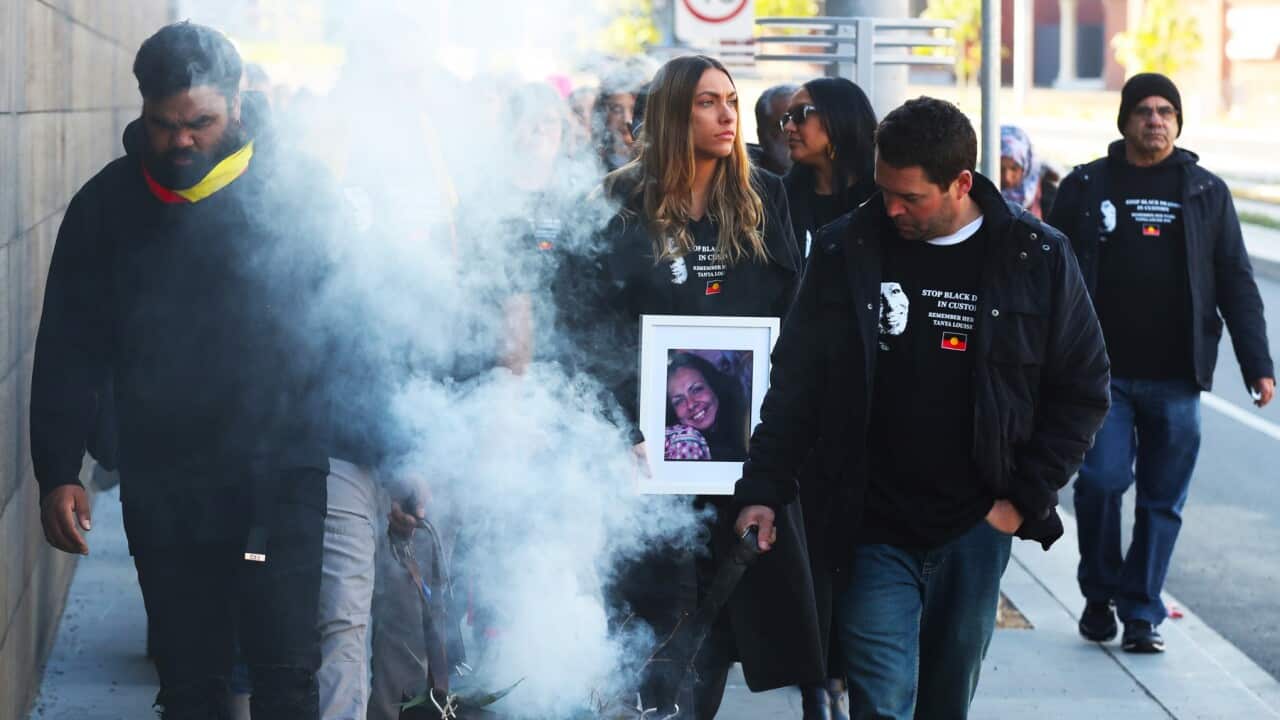 Family members march to the Coroners Court after smoking ceremony in Kings Domain Park