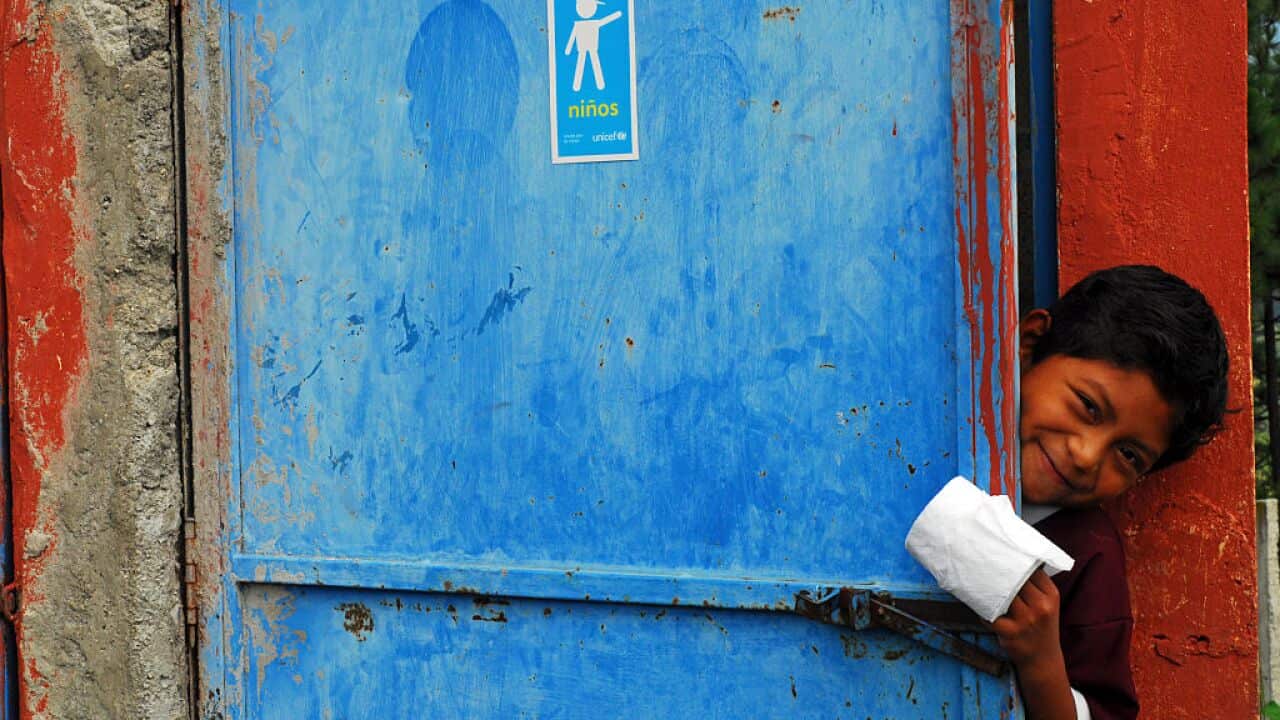 A young boy uses an outdoor latrine