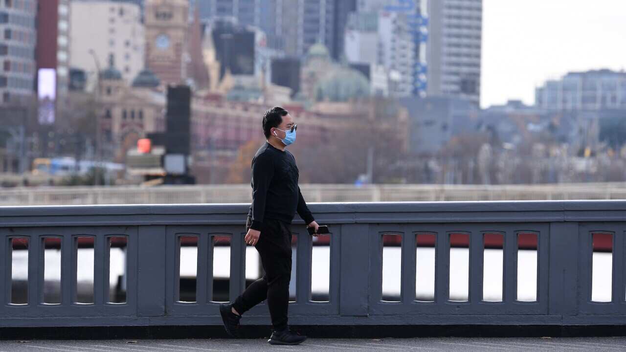 A person wearing a face mask is seen walking across a bridge in Southbank, Melbourne, Saturday, June 5, 2021. Victoria has recorded five new cases of locally acquired coronavirus in the past 24 hours. (AAP Image/James Ross) NO ARCHIVING