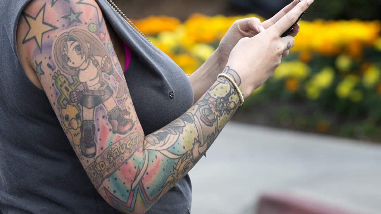 A woman with tattoos is seen texting