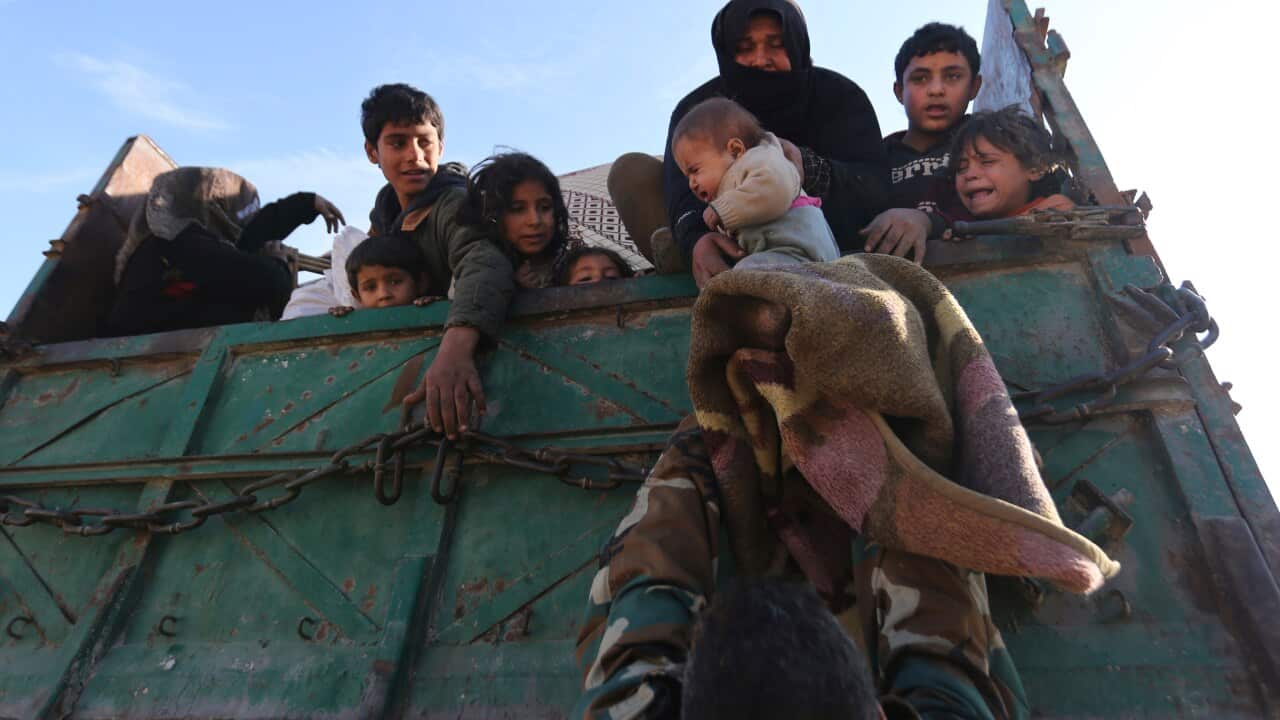 A baby is lifted onto a truck carrying civilians fleeing ahead of a government offensive.