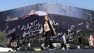 A woman walks in front of a big billboard.