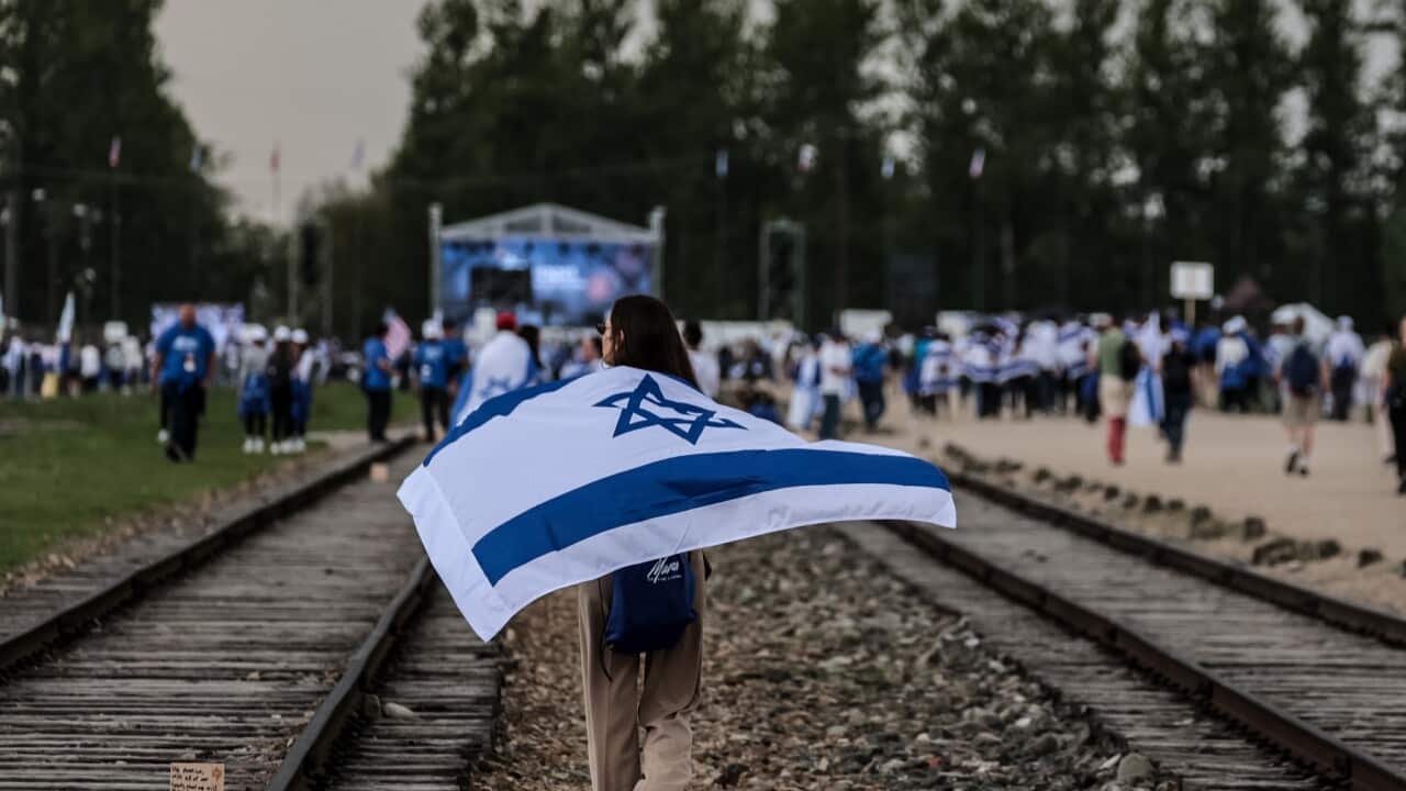 Participants covered with Israeli national flags walk in the International March of the Living at Auschwitz (AAP)