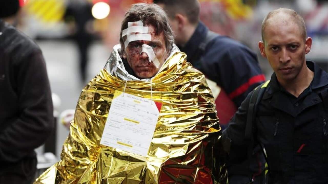 Emergency workers help an injured man at the scene of an explosion at a bakery in Paris.