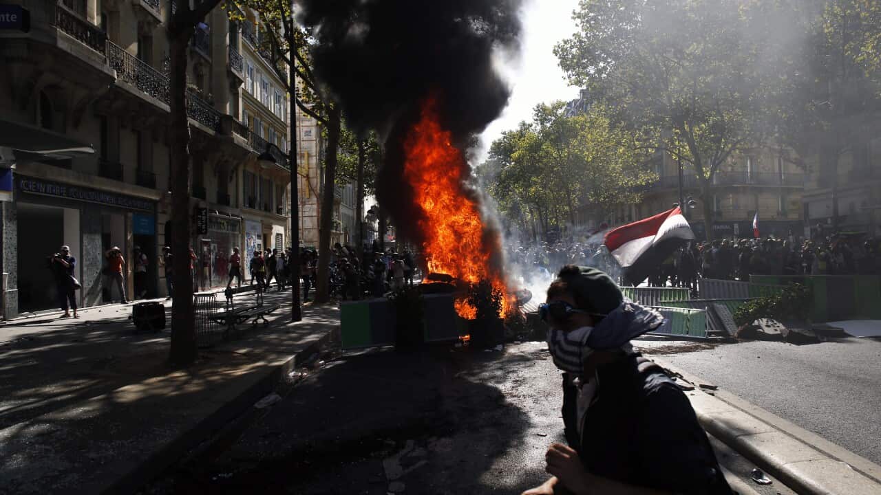 A protester walks past a burning barricade during a climate demonstration, in Paris.