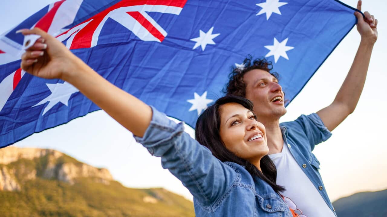Happy couple holding Australian national flag on top of the hill