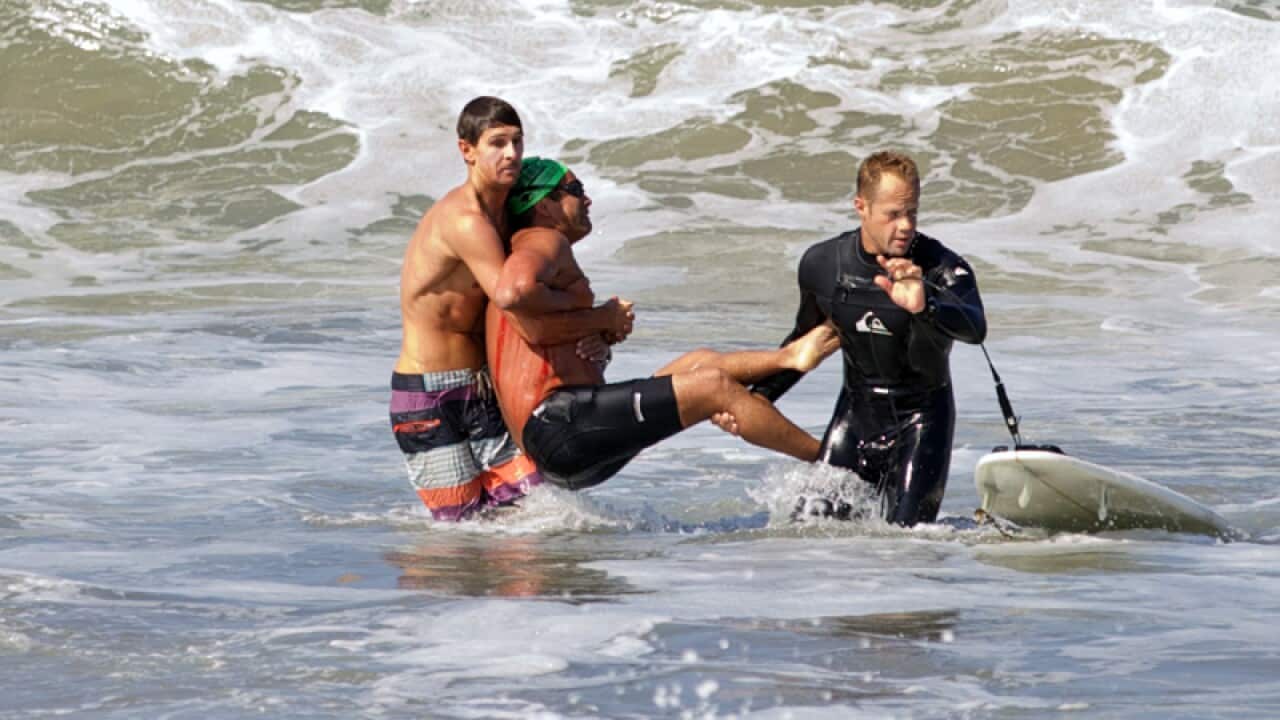 Two men carry a swimmer after he was bitten by a great white shark
